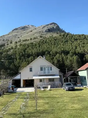 a large house with a mountain in the background at Family house on the mountain - Krstac, Njegusi in Njeguši