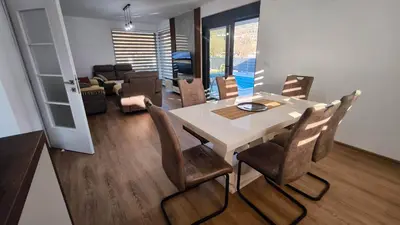 a dining room and living room with a table and chairs at Poolside Idyll in Bar