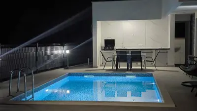 a swimming pool in a room with a table and chairs at Poolside Idyll in Bar