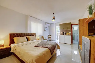 a bedroom with a large bed and a kitchen at Nike's Apartment in Dobra Voda