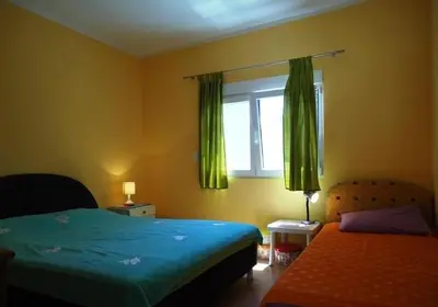 a bedroom with two beds and a window with green curtains at Iva Guest House in Sutomore