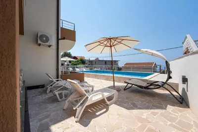 a patio with chairs and an umbrella and a pool at Four Seasons Villa Valentina in Kotor