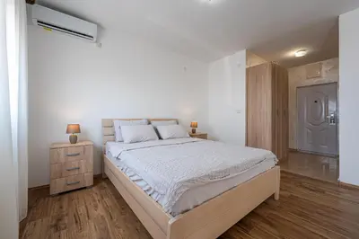 a white bedroom with a large bed and a wooden floor at Four Seasons Villa Valentina in Kotor