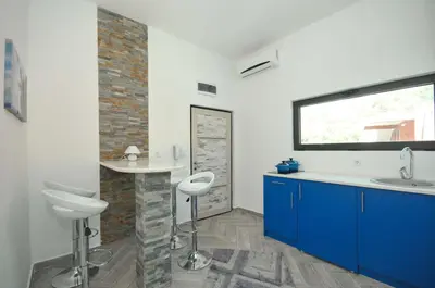 a bathroom with a sink and a counter with two stools at Apartments Jadranski Biser in Čanj