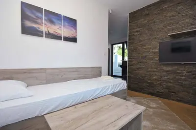 a bedroom with a large bed and a flat screen tv at Apartments Jadranski Biser in Čanj