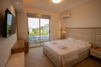 a bedroom with a bed and a balcony with a table at Amber Lux Apartments in Ulcinj