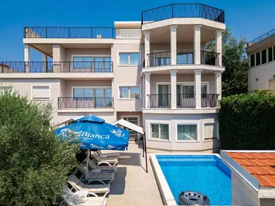 an apartment building with a swimming pool and an umbrella at Luxury Villa Boričić in Kotor