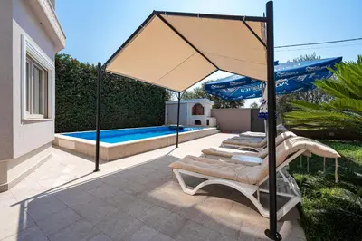 a group of lounge chairs under an umbrella next to a swimming pool at Luxury Villa Boričić in Kotor