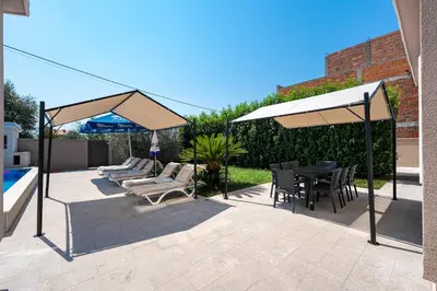 a patio with chairs and a table and umbrellas at Luxury Villa Boričić in Kotor