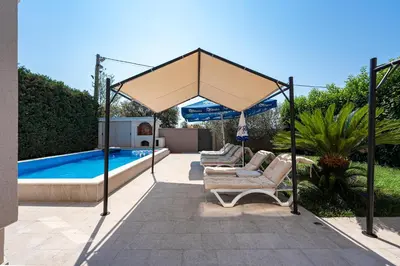 a large umbrella over chairs and a swimming pool at Luxury Villa Boričić in Kotor