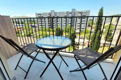 a glass table and two chairs on a balcony at Urban Escape Apartment in Pobrežje