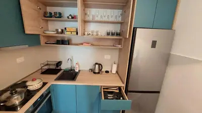 a small kitchen with blue cabinets and a refrigerator at Urban Escape Apartment in Pobrežje