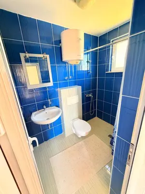 a blue tiled bathroom with a toilet and a sink at Velic in Ulcinj