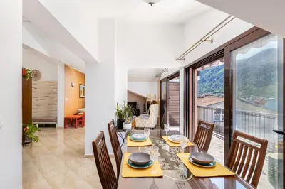 a dining room with a table and chairs and a balcony at LuSi SeaView Apartment in Kotor