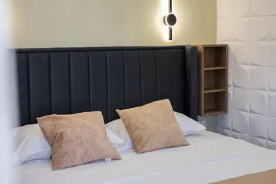 a bed with a black headboard and two pillows at Hana Apartments in Ulcinj