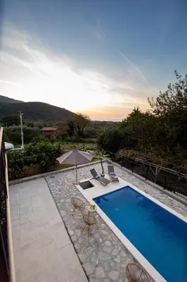 a swimming pool with two chairs and an umbrella at Stone Villa with pool Montenegro Star in Kaluđerac