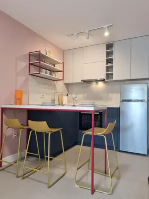 a kitchen with three chairs and a counter and a refrigerator at Petrovac modern apartment in Petrovac na Moru