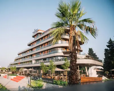 a hotel with a palm tree in front of it at Luxury Apartment with Green Terrace, Porto Milena View and Private Garage in Ulcinj