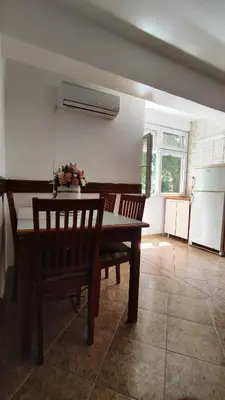 a dining room with a table and chairs and a kitchen at Apartman Centar Bar in Bar