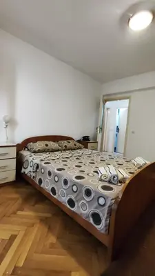 a large bed in a bedroom with a wooden floor at Apartman Centar Bar in Bar