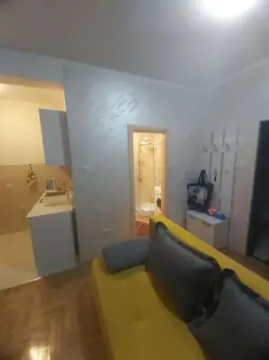 a living room with a yellow couch and a kitchen at Apartman Manja Petrovac in Petrovac na Moru
