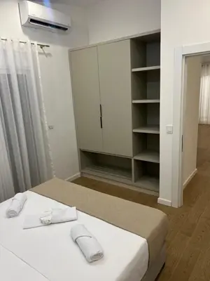 a white bedroom with a bed and a closet at Sunny apartments in Ulcinj
