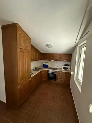 a small kitchen with wooden cabinets and a window at Stellax Apartment in Donji Štoj