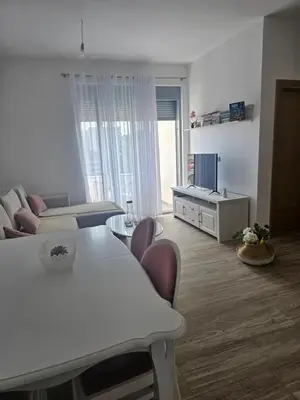 a white living room with a table and a couch at SOL Apartment in Ulcinj