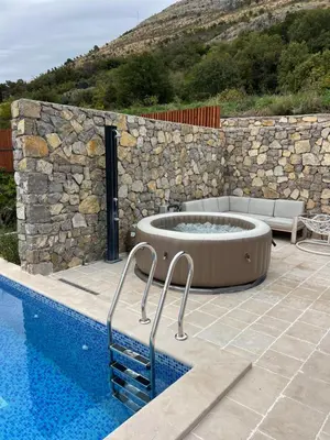 a swimming pool with a tub next to a stone wall at Villa Mare in Petrovac na Moru