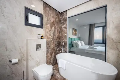 a bathroom with a tub and a toilet and a bed at Villa Mare in Petrovac na Moru