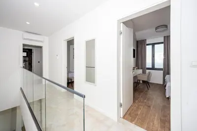 a hallway with white walls and a glass stairway at Villa Mare in Petrovac na Moru