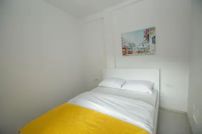 a small white room with a bed with a yellow blanket at Vila Varagic in Budva