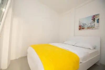 a white bedroom with a yellow blanket on a bed at Vila Varagic in Budva