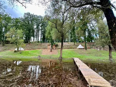 a wooden bridge over a pond in a park at Zeta River Glamping in Danilovgrad