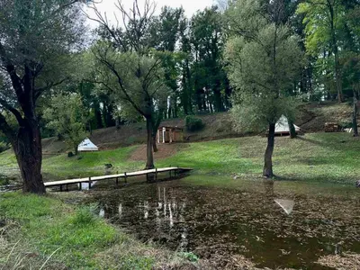 a body of water with trees and a bridge at Zeta River Glamping in Danilovgrad