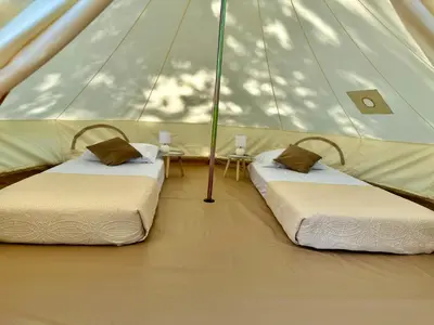 two beds in a tent with a table at Zeta River Glamping in Danilovgrad