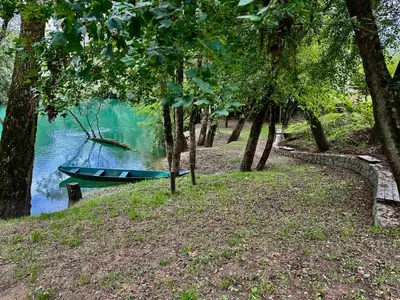 a boat sitting on the side of a river with trees at Zeta River Glamping in Danilovgrad