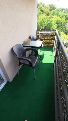 two chairs and a table on a balcony with green flooring at Urban Retreat Dalmatinska in Podgorica
