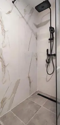 a bathroom with a shower with a marble wall at Elegant Apartment with Urban Charm in Podgorica