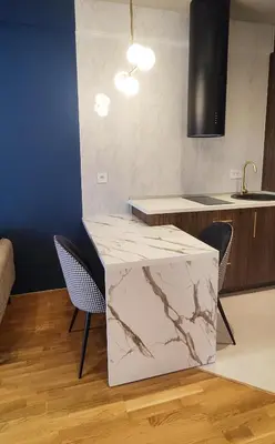 a kitchen with a marble counter and chairs at Elegant Apartment with Urban Charm in Podgorica