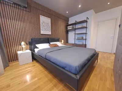 a bedroom with a large bed and a wooden floor at Design Apartment with Panoramic Views in Podgorica