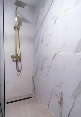 a shower in a bathroom with white marble walls at Design Apartment with Panoramic Views in Podgorica