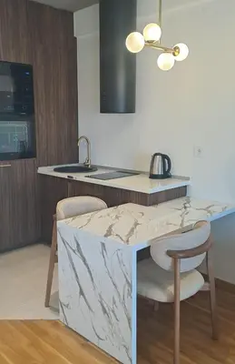 a kitchen with a marble counter top and two chairs at Design Apartment with Panoramic Views in Podgorica