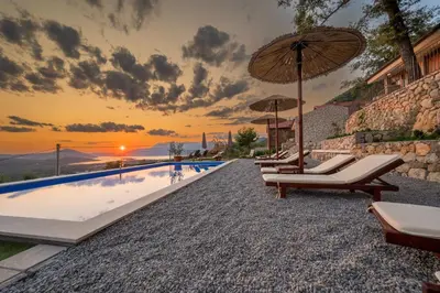 a swimming pool with lounge chairs and an umbrella at Case del Tramonto in Kotor