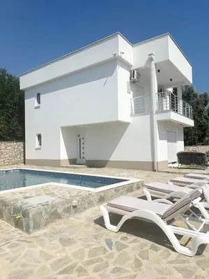 a white house with a swimming pool and lounge chairs at L U X V I L A, Dobre Vode in Dobra Voda