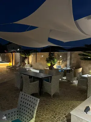 a restaurant with tables and chairs under a large umbrella at Aquamarine Jaz Montenegro in Budva