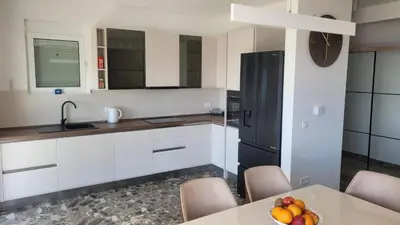 a kitchen with white cabinets and a table with a bowl of fruit at Villa Moonlight in Budva
