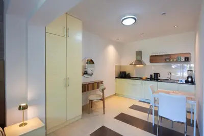 a kitchen with white cabinets and a table and chairs at Torch Apartments in Budva