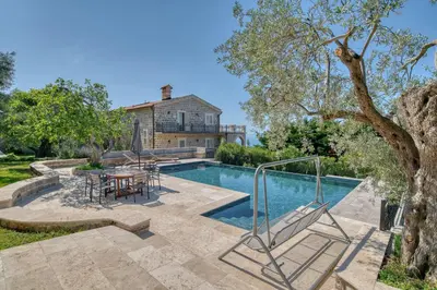 a pool with a table and chairs next to a house at Villa Olive Grove in Budva