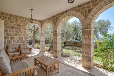 an outdoor living room with a stone wall and arches at Villa Olive Grove in Budva